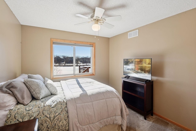 carpeted bedroom featuring visible vents, baseboards, a textured ceiling, and a ceiling fan