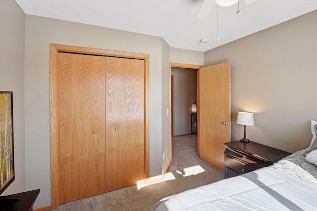 carpeted bedroom with a closet, baseboards, and ceiling fan