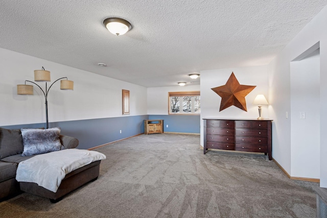 sitting room with a textured ceiling, baseboards, and carpet