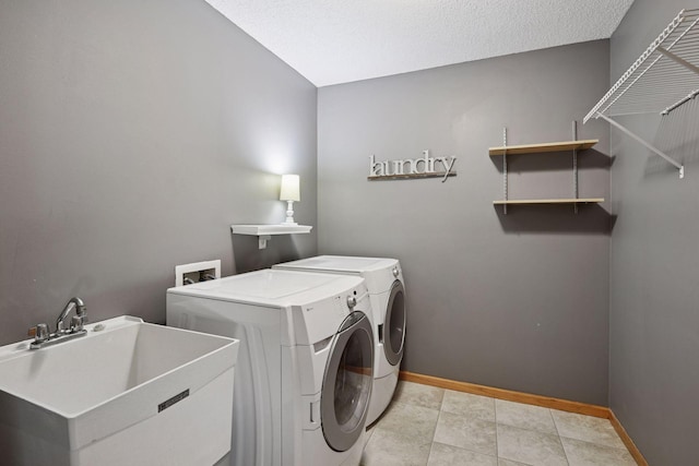 washroom featuring a sink, baseboards, laundry area, a textured ceiling, and separate washer and dryer