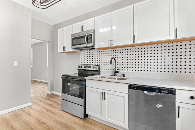 kitchen with sink, white cabinets, light hardwood / wood-style floors, and appliances with stainless steel finishes