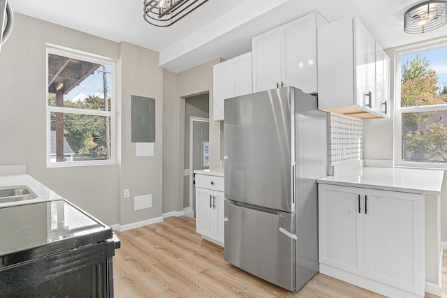 kitchen with electric panel, stainless steel fridge, light hardwood / wood-style flooring, and white cabinets