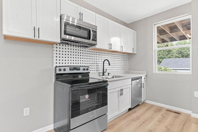 kitchen featuring white cabinets, light hardwood / wood-style floors, sink, and appliances with stainless steel finishes