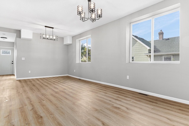 unfurnished dining area featuring light hardwood / wood-style flooring and a notable chandelier