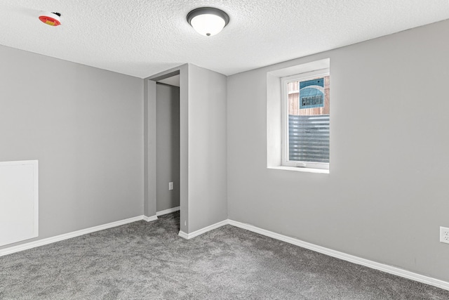 empty room featuring a textured ceiling and dark carpet