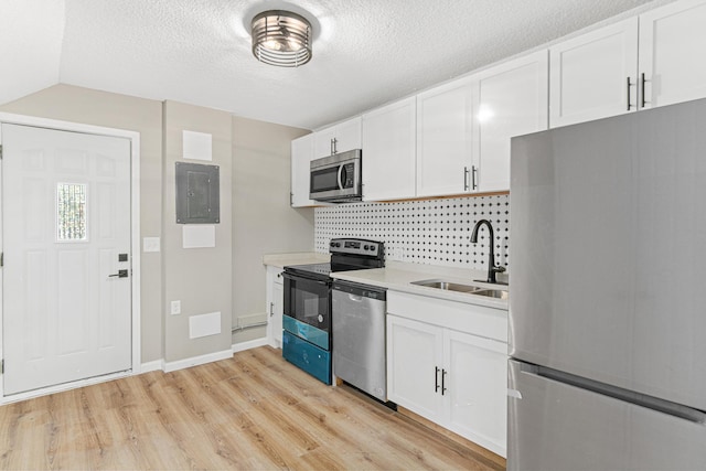 kitchen featuring sink, stainless steel appliances, tasteful backsplash, electric panel, and white cabinets