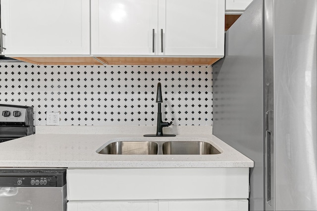 kitchen featuring backsplash, sink, light stone counters, white cabinetry, and stainless steel appliances