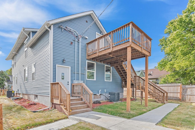 rear view of house featuring cooling unit, a yard, and a wooden deck