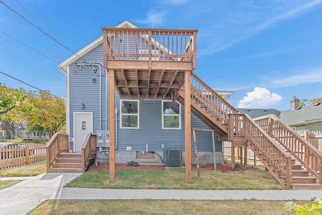 view of front of home featuring a front lawn, cooling unit, and a wooden deck