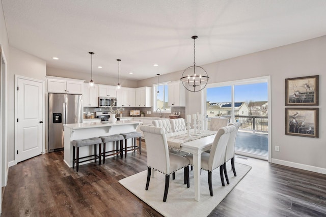 dining area with dark wood-type flooring, an inviting chandelier, and sink