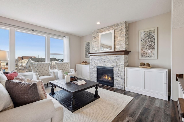 living room with a stone fireplace, dark hardwood / wood-style floors, and a textured ceiling