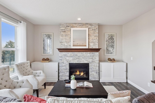 living room featuring a stone fireplace, dark hardwood / wood-style flooring, and a textured ceiling