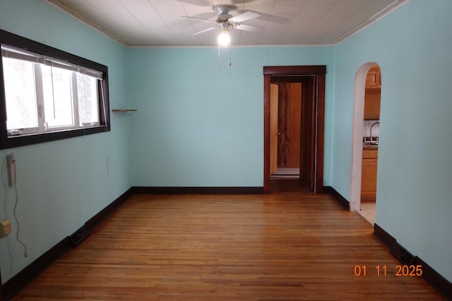 empty room with ceiling fan, hardwood / wood-style flooring, and crown molding