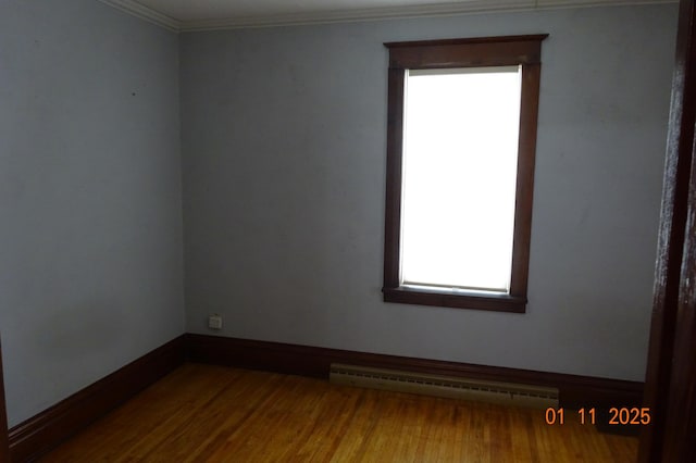 spare room featuring hardwood / wood-style flooring, baseboard heating, and ornamental molding