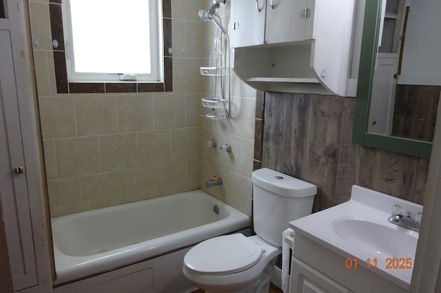 full bathroom featuring toilet, vanity, wood walls, and tiled shower / bath