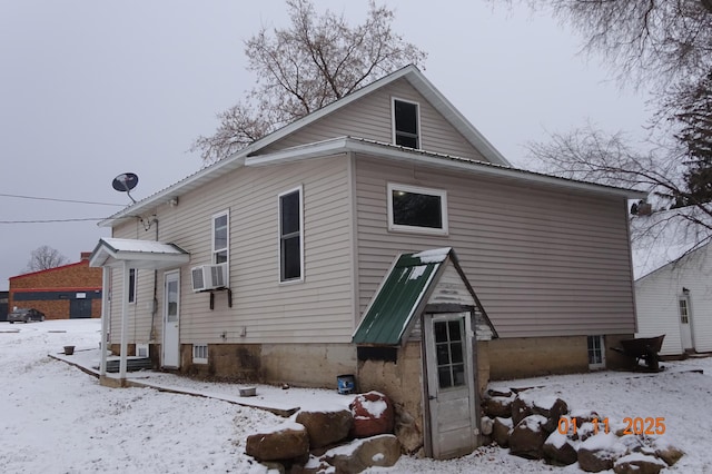 snow covered house featuring cooling unit