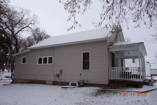 snow covered rear of property with covered porch