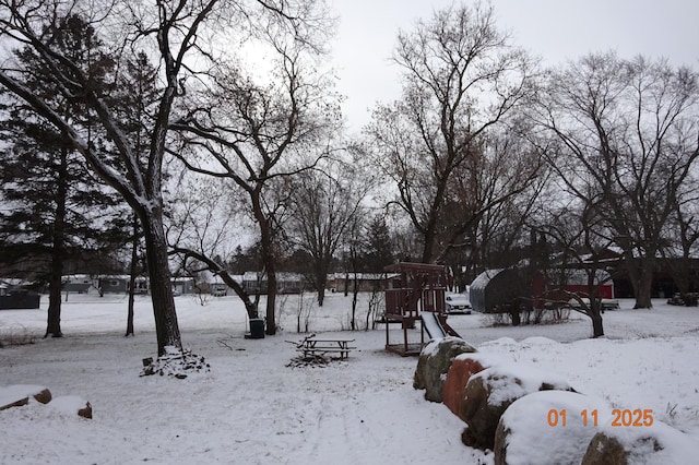 yard covered in snow featuring a playground