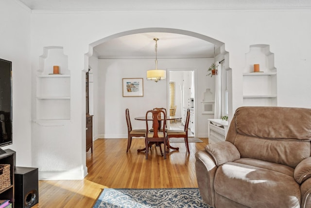 dining space with light hardwood / wood-style floors, ornamental molding, and built in shelves