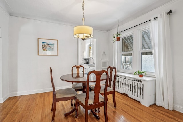 dining space featuring sink, light hardwood / wood-style flooring, and crown molding