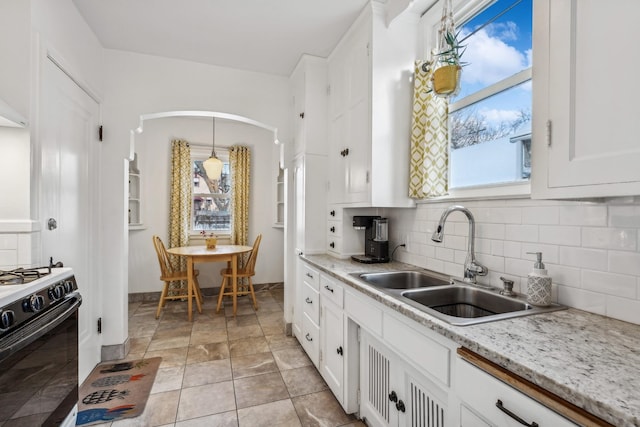 kitchen featuring gas range oven, decorative light fixtures, tasteful backsplash, white cabinets, and sink