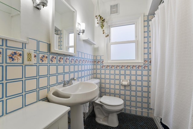 bathroom featuring toilet, tile patterned flooring, tile walls, and curtained shower