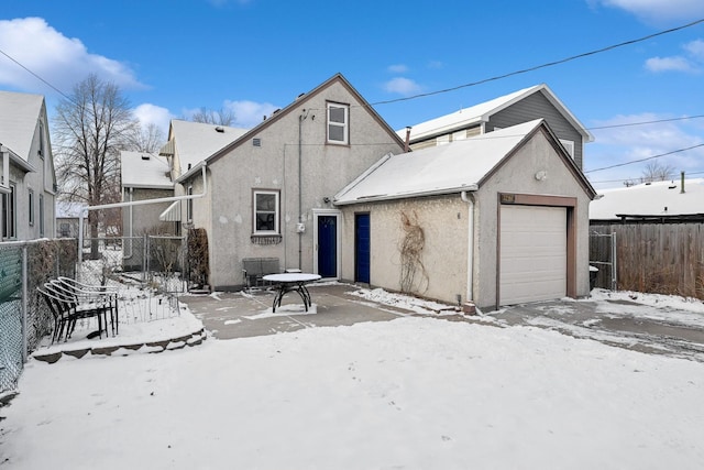 snow covered rear of property featuring a garage