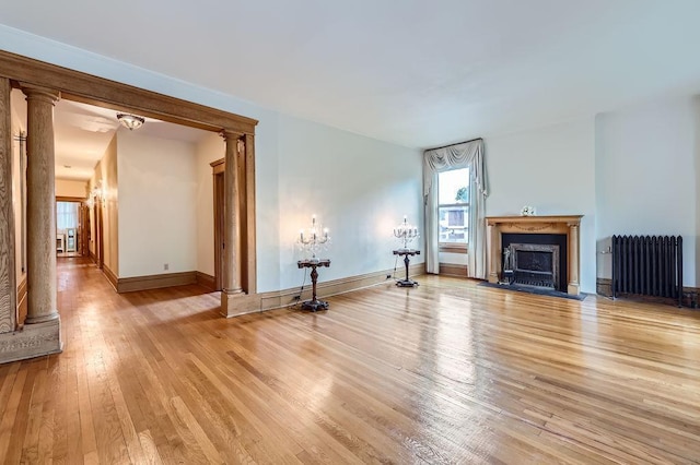 442 Summit Ave Unit 6, Saint Paul, MN 55102 - unfurnished living room with radiator, decorative columns, light wood-style floors, and a fireplace with flush hearth