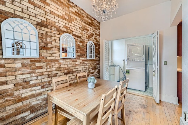 442 Summit Ave Unit 6, Saint Paul, MN 55102 - dining room with stacked washer and clothes dryer, brick wall, a chandelier, and light wood-style flooring
