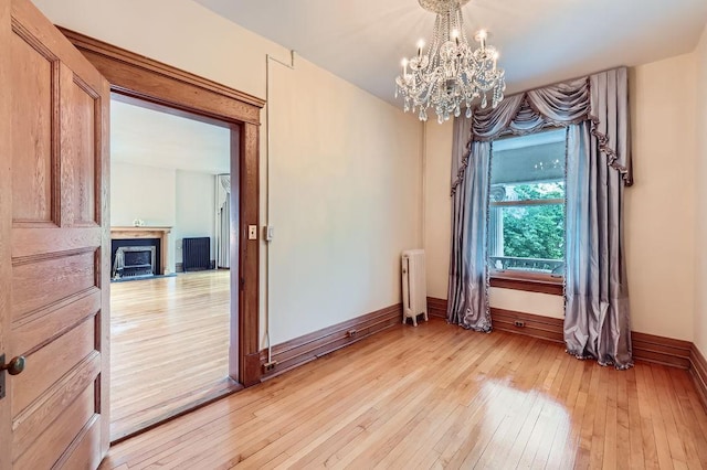 442 Summit Ave Unit 6, Saint Paul, MN 55102 - spare room featuring radiator, a chandelier, light wood finished floors, and a fireplace