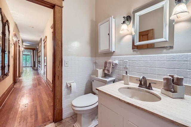442 Summit Ave Unit 6, Saint Paul, MN 55102 - half bath with tile walls, vanity, a wainscoted wall, and wood finished floors