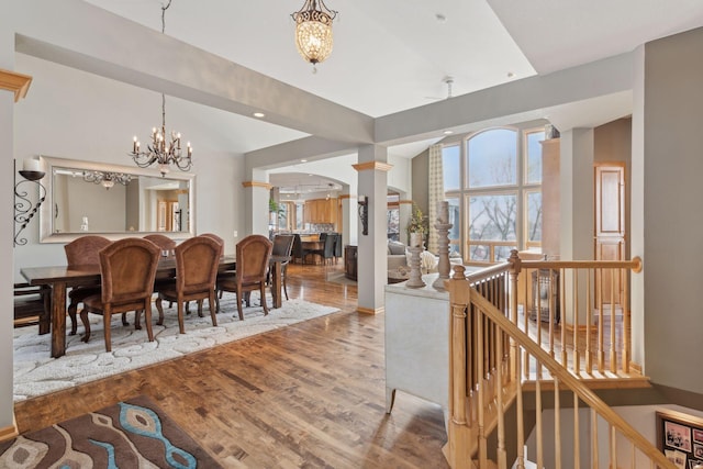 dining space with an inviting chandelier, hardwood / wood-style floors, and ornate columns