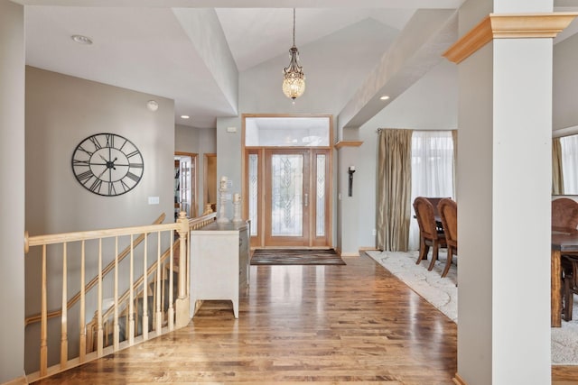 foyer entrance with wood-type flooring, lofted ceiling, and a notable chandelier