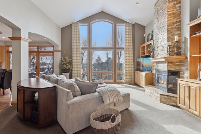 living room with a fireplace, plenty of natural light, high vaulted ceiling, and ornate columns