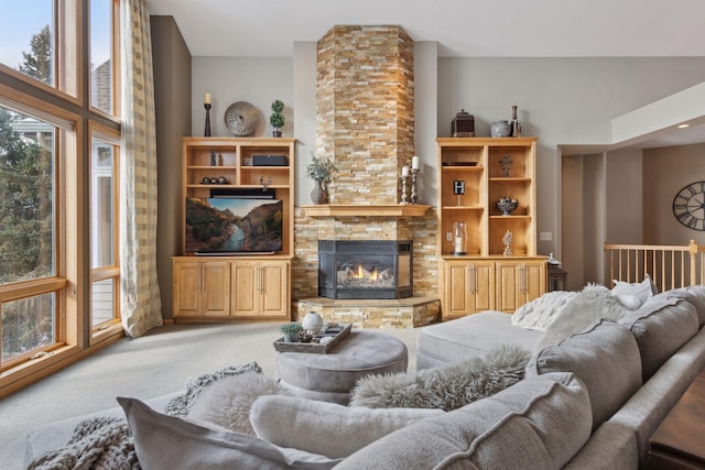 carpeted living room featuring a stone fireplace