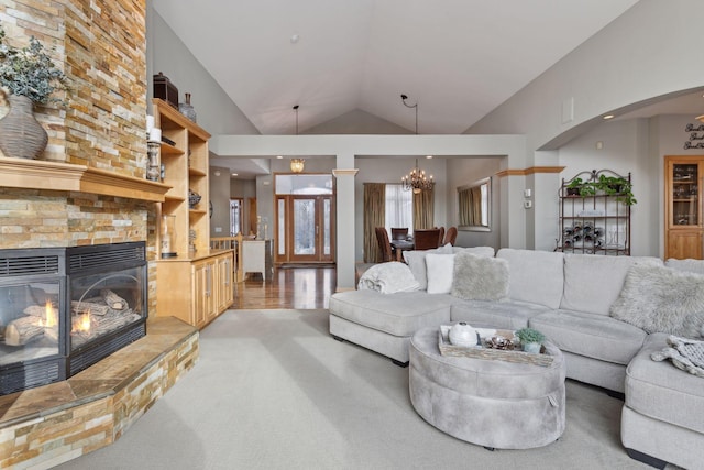 living room with an inviting chandelier, vaulted ceiling, a large fireplace, and light carpet