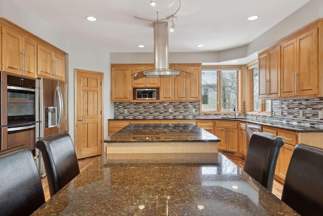 kitchen featuring sink, appliances with stainless steel finishes, backsplash, a kitchen island, and dark stone counters