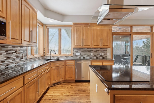 kitchen featuring sink, dark stone countertops, decorative backsplash, stainless steel appliances, and light hardwood / wood-style flooring