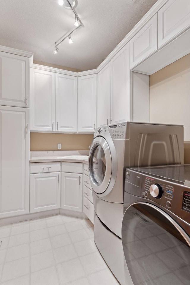 clothes washing area with cabinets, washer and dryer, and a textured ceiling