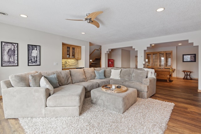 living room featuring ceiling fan, wood-type flooring, sink, and a textured ceiling