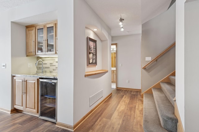 interior space with a textured ceiling, indoor wet bar, wine cooler, and light hardwood / wood-style floors