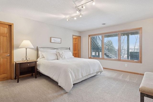 bedroom with carpet flooring, track lighting, and a textured ceiling