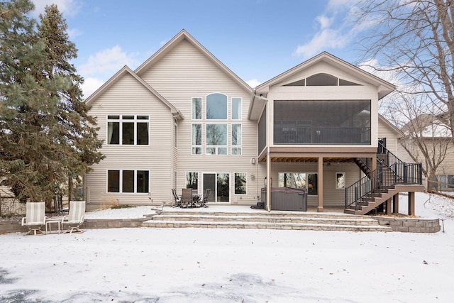 snow covered property with a hot tub and a sunroom