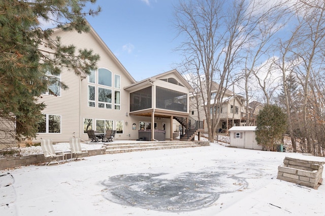 snow covered property featuring a hot tub, a sunroom, a patio area, and a shed