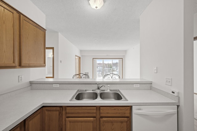 kitchen with a textured ceiling, dishwasher, kitchen peninsula, and sink