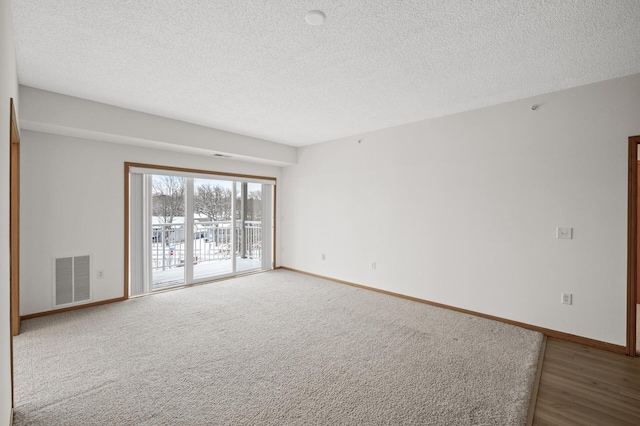 carpeted empty room with a textured ceiling