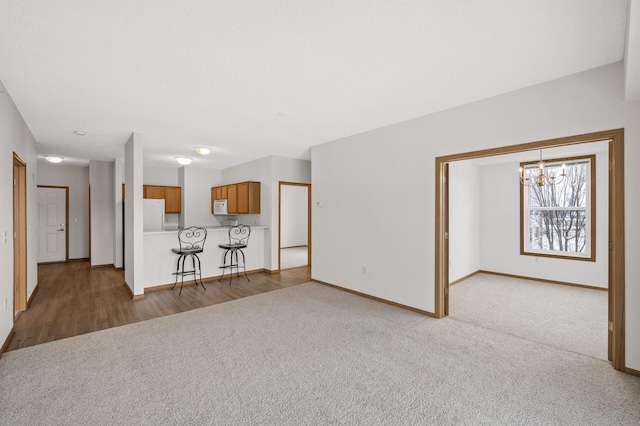 unfurnished living room with carpet flooring and a notable chandelier