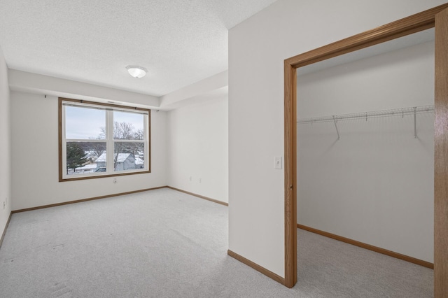 unfurnished bedroom with light carpet, a textured ceiling, and a closet