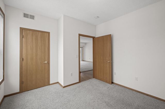 unfurnished bedroom with light colored carpet and a closet