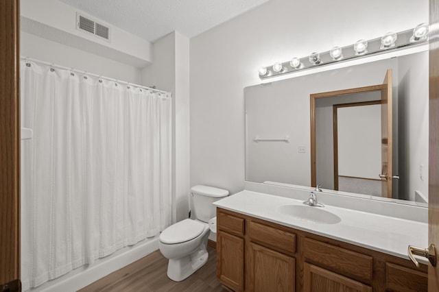 bathroom featuring hardwood / wood-style floors, vanity, toilet, a textured ceiling, and walk in shower